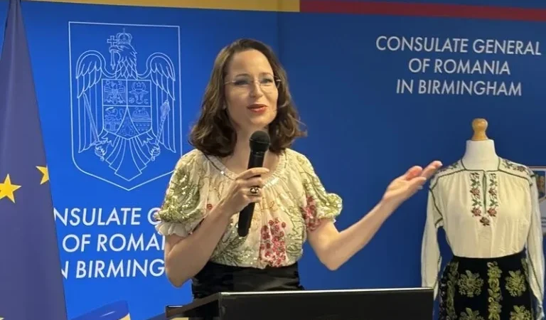 A speaker at the Consulate General of Romania in Birmingham on Romania Blouse Day, beside a traditional ia blouse