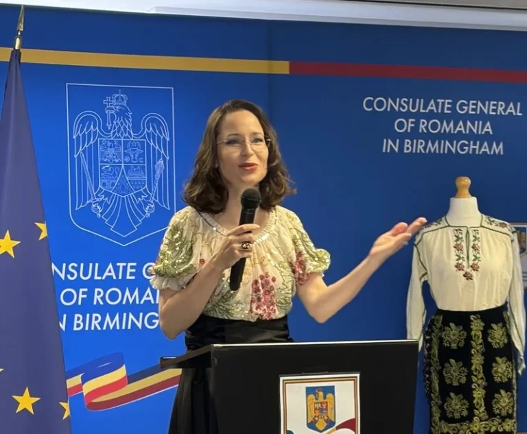 A speaker at the Consulate General of Romania in Birmingham on Romania Blouse Day, beside a traditional ia blouse