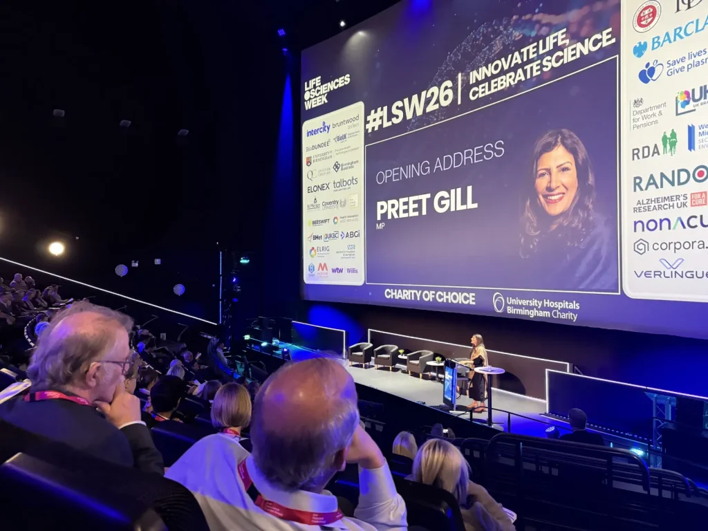 Preet Gill MP gives the opening address at Life Sciences Week 2026, with her name on the big screen above the stage