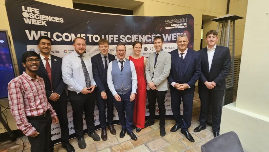 Paul Cadman, second from right, with guests in front of the Welcome to Life Sciences Week board