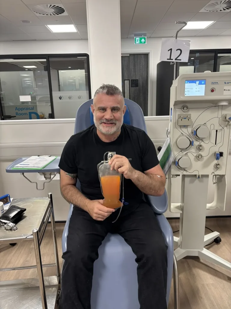 Paul Cadman holding a bag of donated plasma at a donor centre