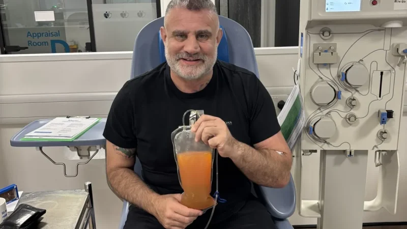 Paul Cadman holding a bag of donated plasma at a donor centre