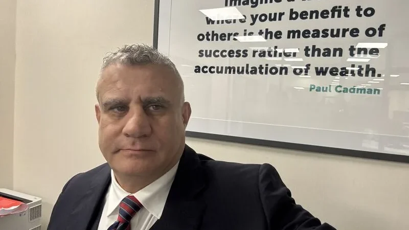 Paul Cadman in front of his motto on an office wall
