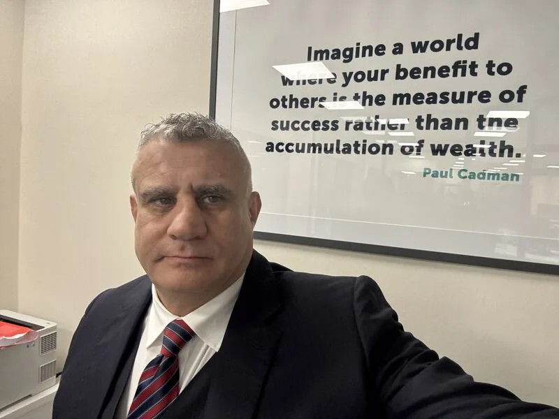 Paul Cadman in front of his motto on an office wall